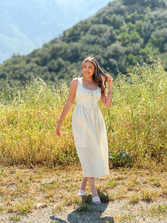 Woman in a white dress standing in a field with mountains in the background