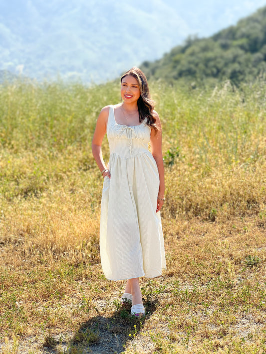 Woman in a white dress standing in a field with mountains in the background