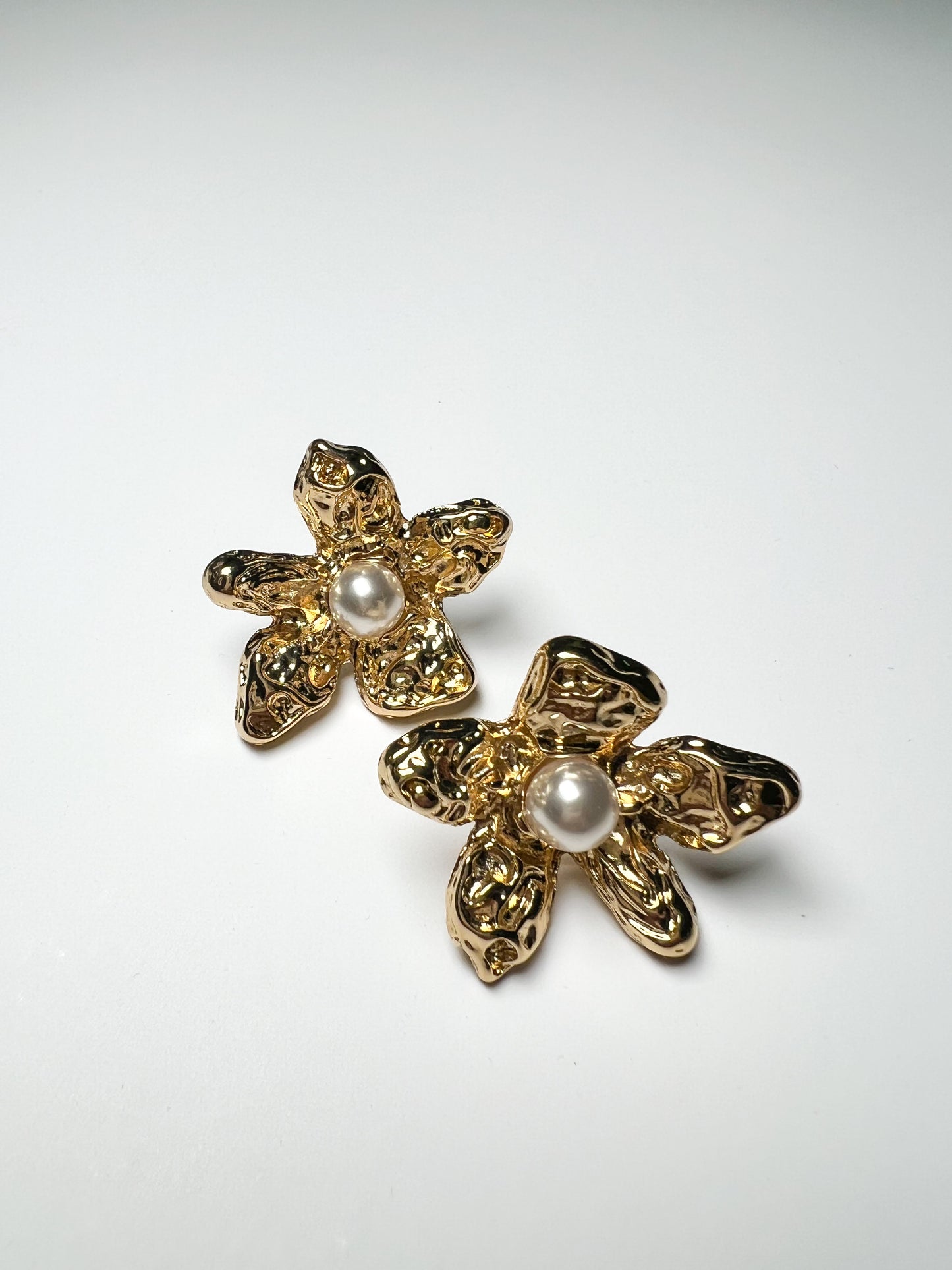 Gold floral earrings with pearl centers on a white background