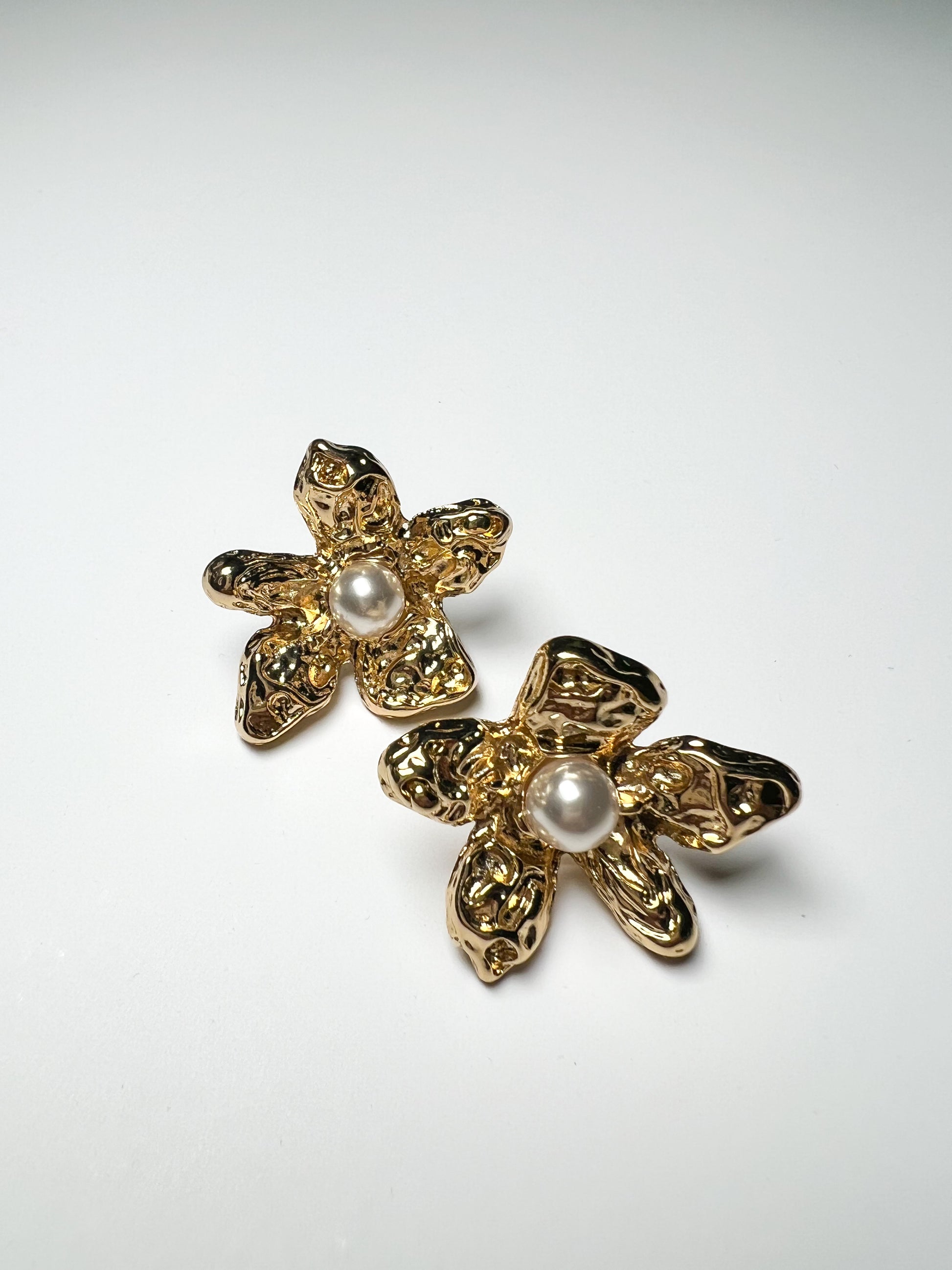 Gold floral earrings with pearl centers on a white background