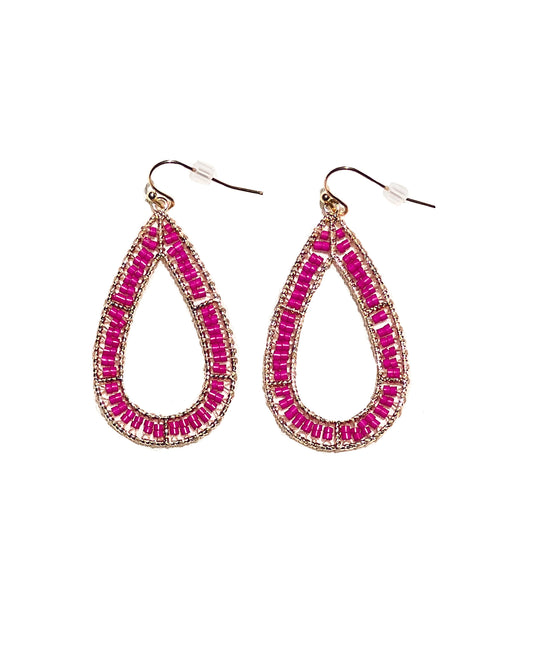 A close-up detail of hot pink earrings with beaded material. Has an oval shape and has plastic backing. 
