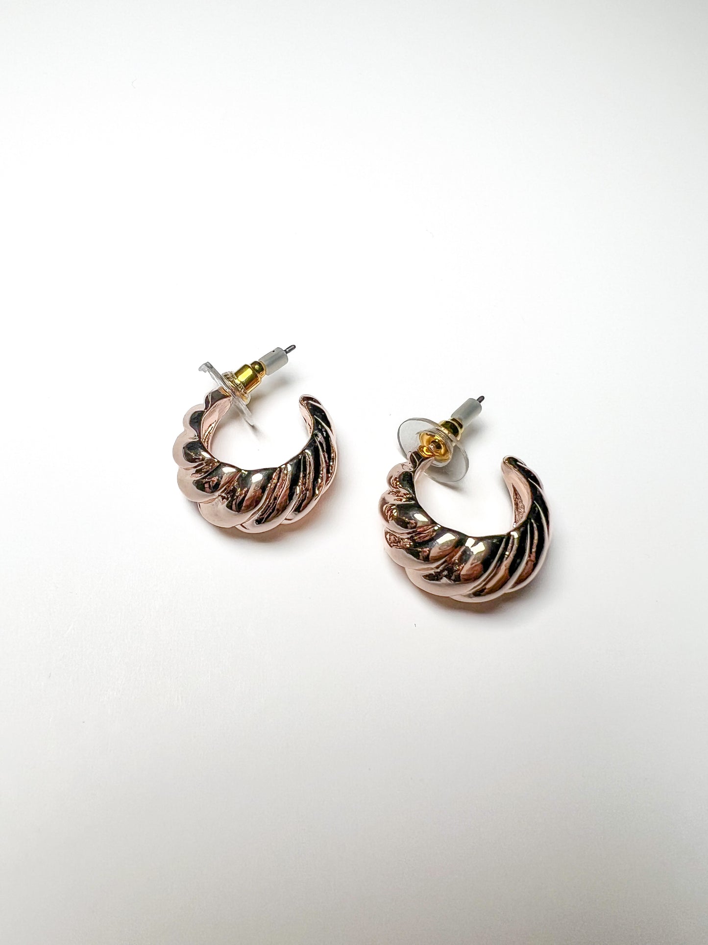 Pair of hoop earrings with a gold and rose gold finish on a white background