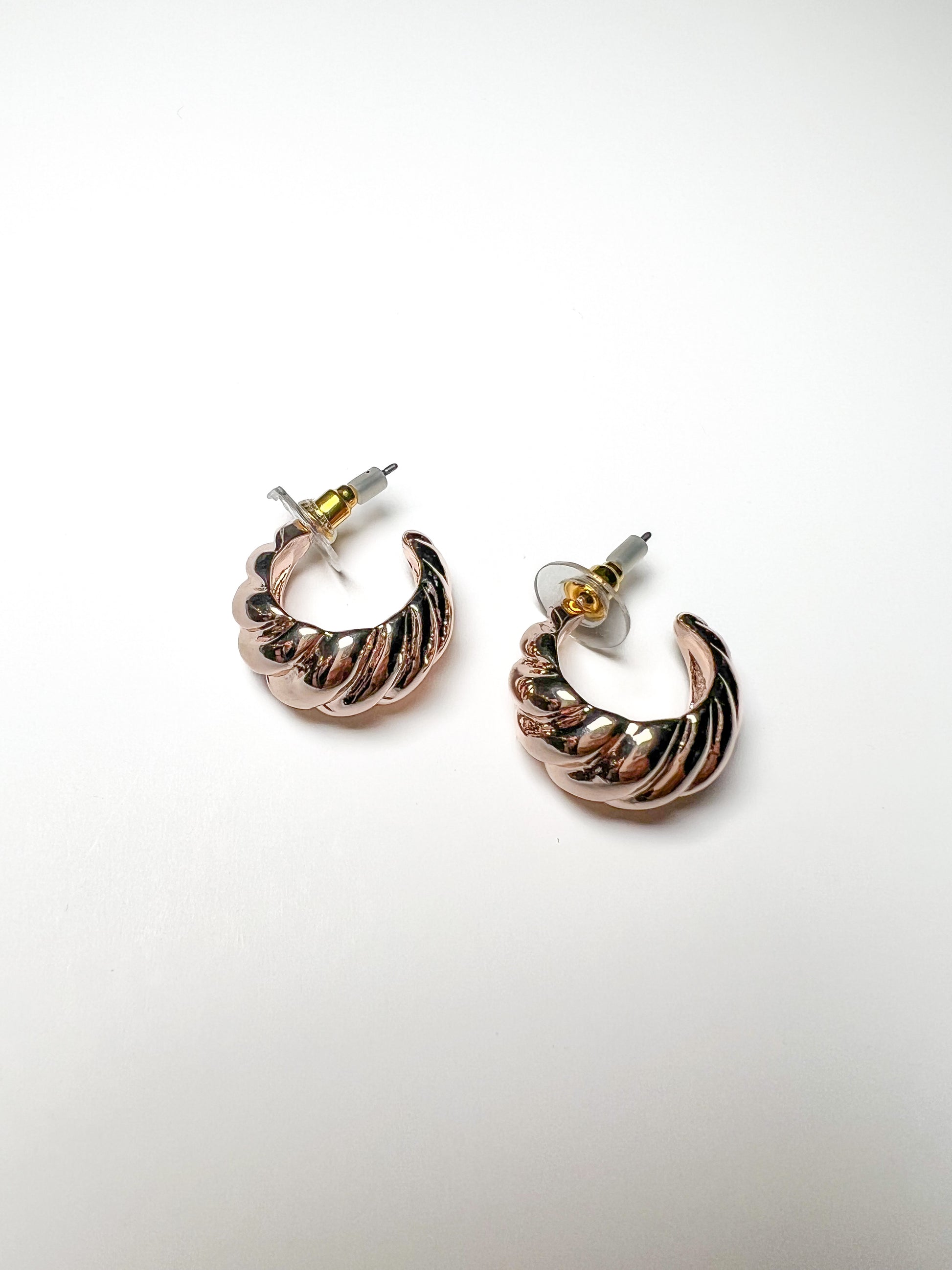 Pair of hoop earrings with a gold and rose gold finish on a white background