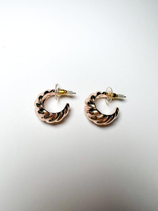 Pair of gold hoop earrings on a light gray background