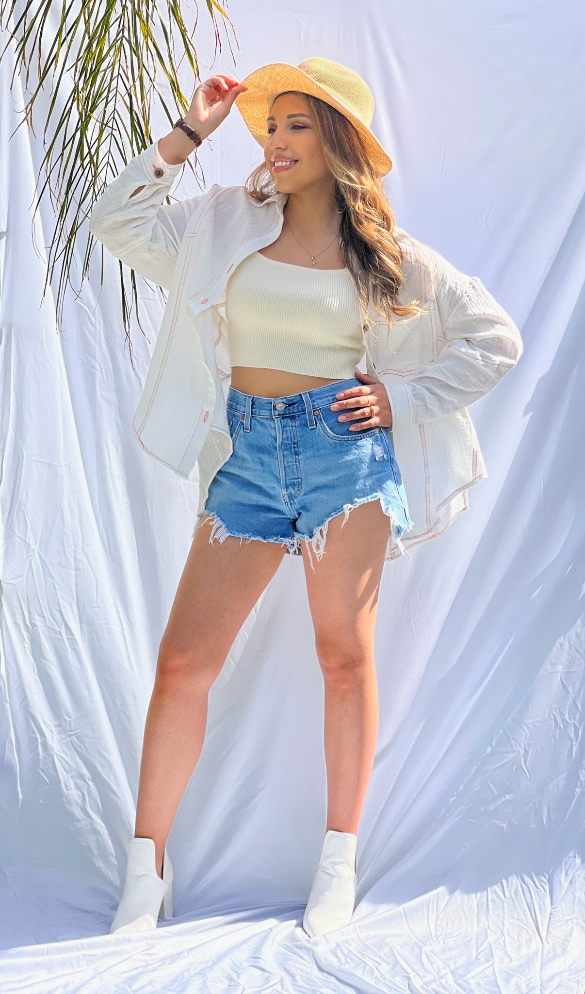 A latina model is wearing an off-white ribbed knit crop top. It has a square neckline and wide shoulder straps. She is modeling it with denim shorts and a white pull-over oversized shirt. Hit the beach in our "Chasing Sunsets Ribbed Knit Top". Get creative and style it for a day to night look! Beautiful square neck, with wide shoulders straps, and cropped hem. Stretchy ribbed knit provides a flattering fit. Square Neck. Wide Shoulder Straps. 56% Rayon, 22% Nylon, and 22% Polyester Model wearing size small.