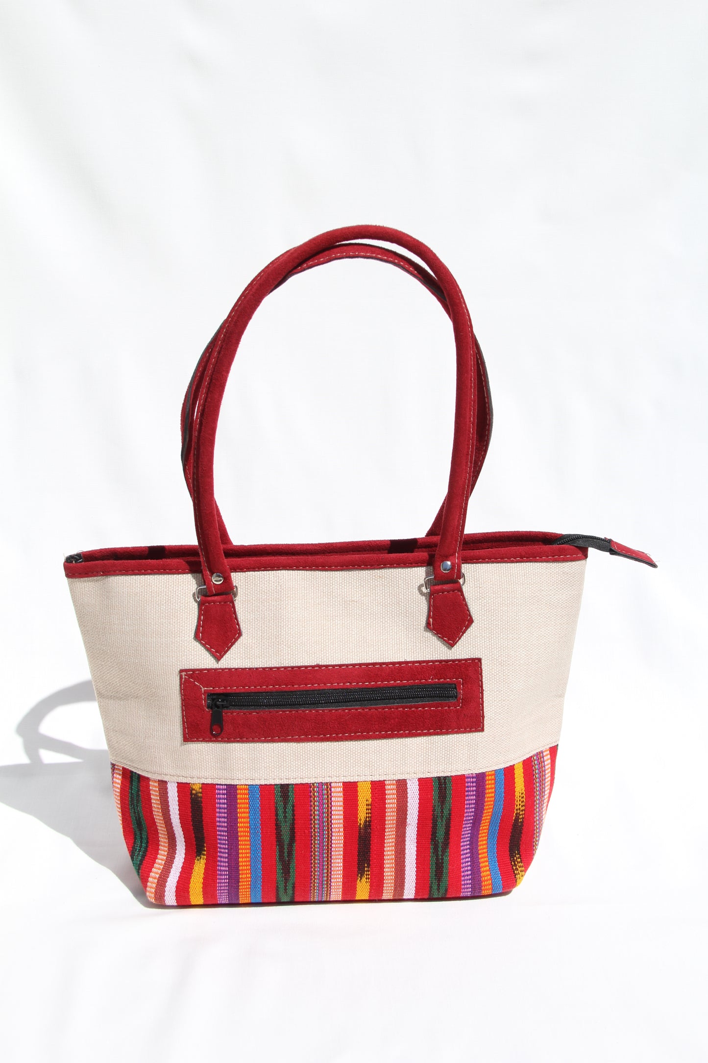 Back view of a handwoven handbag with a bottom panel of intricate Guatemalan fabric with red faux suede shoulder straps and top zipper closure to protect essential items from falling out. the prefect travel, hiking or beach bag unique bag great for your next destination boho bag and hippie style bag a great standout accessories made in Guatemala