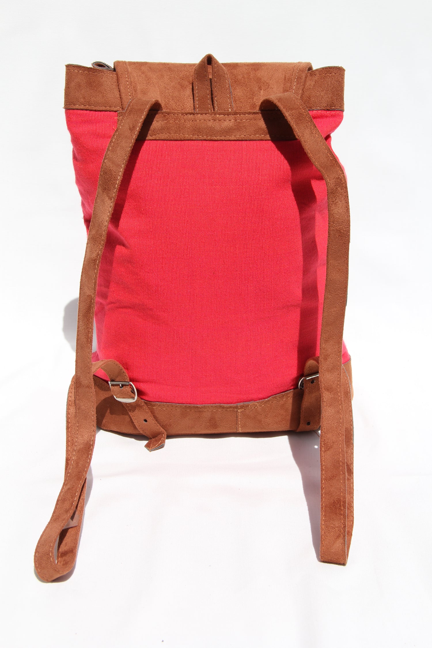 This is the backside of the backpack. It's placed on a solid white background. The back side of the bag is solid corral and it includes two brown faux suede shoulder straps. They can be adjusted to whatever length you'd like. 