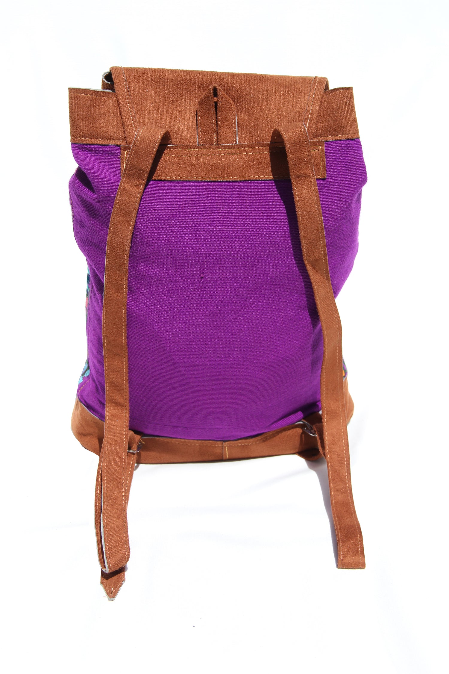 This is the backside of the backpack. It's placed on a solid white background. The back side of the bag is solid purple and it includes two brown faux suede shoulder straps. They can be adjusted to whatever length you'd like.