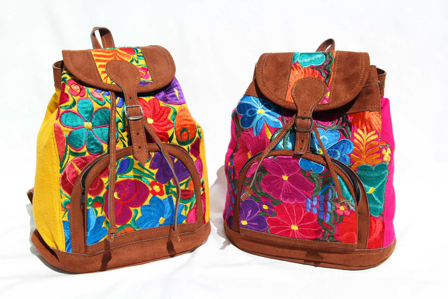 Two colorful huipil floral embroidery backpacks in yellow and pink woven fabric and faux suede contrast with adjustable straps and front buckle closure with front zipper pocket the prefect travel, hiking or beach bag unique bag great for back to school take this bag on your next destination boho bag and hippie style bag a great standout accessories made in Guatemala